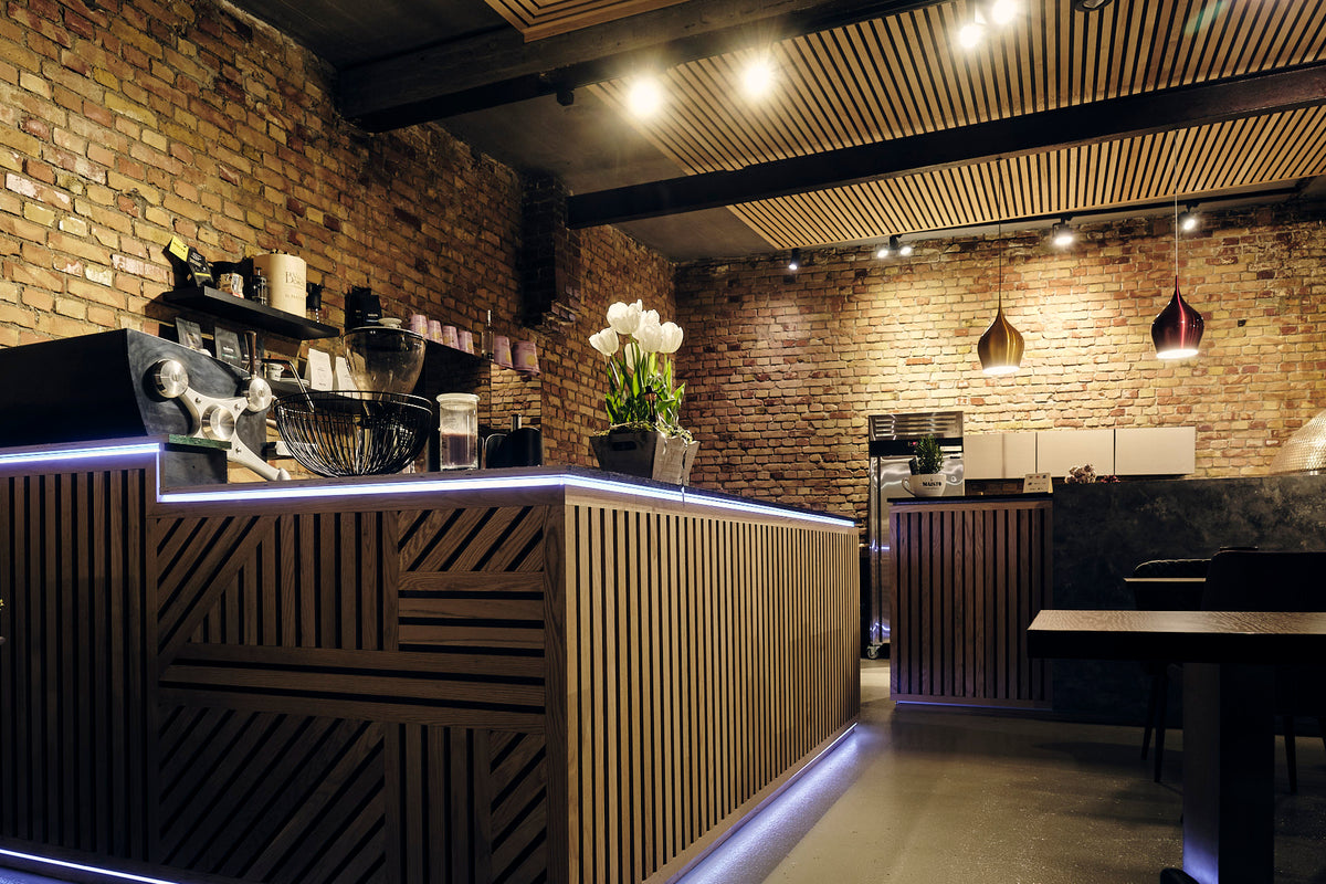 Innenraum des Maisto Caffè mit Backsteinwand, Holztheke und warmem Licht